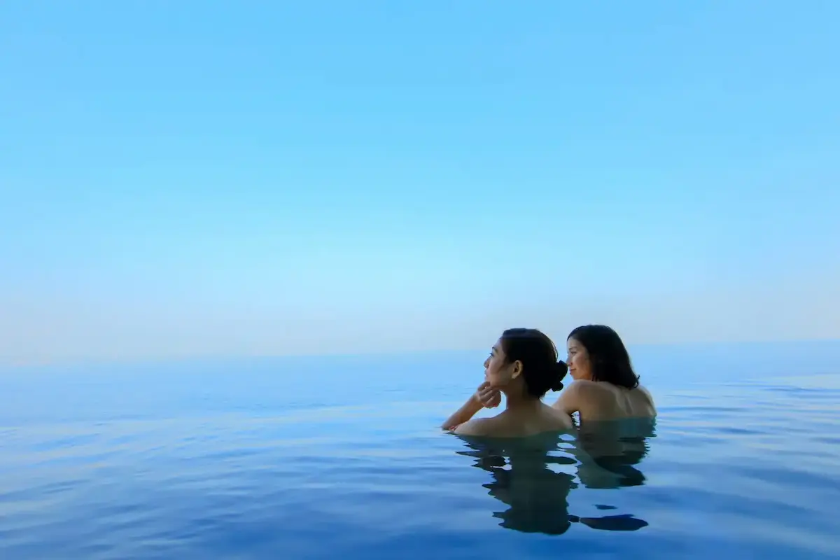 熱海の人気日帰り温泉施設「オーシャンスパ Fuua」の「露天立ち湯」に入浴する2人の女性の様子
